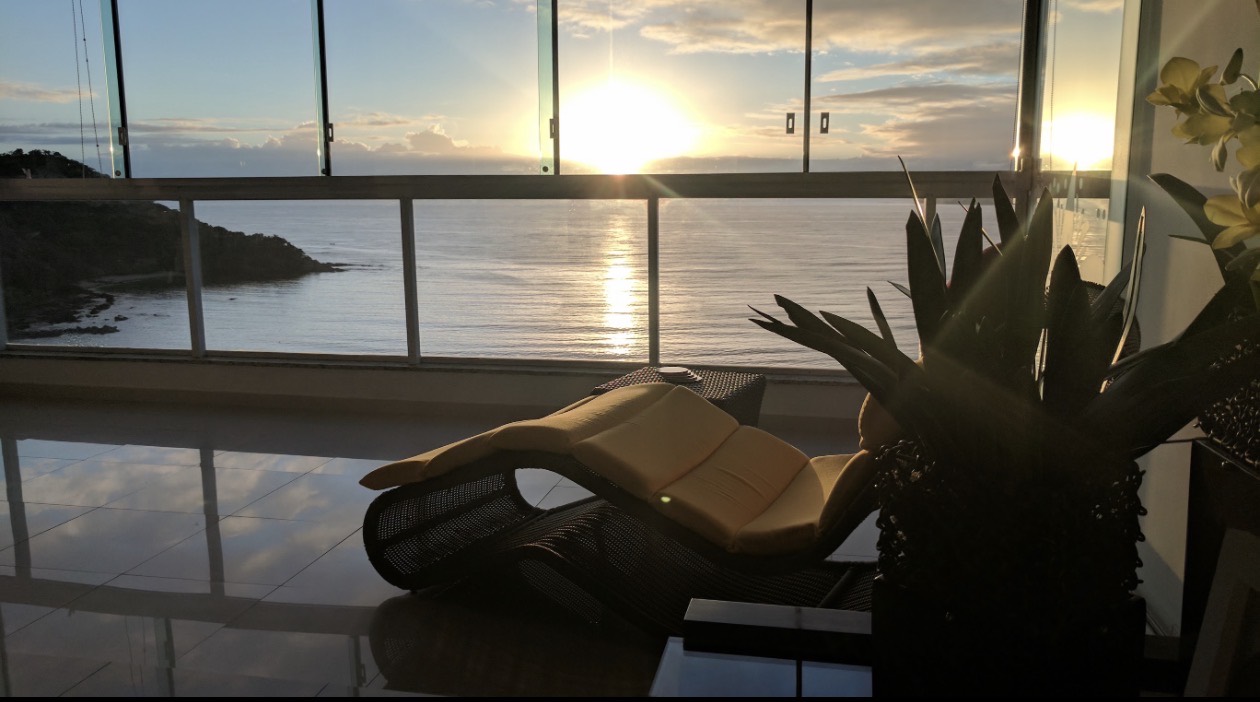 The same yellow lounge chair framed by plants and the Atlantic sunrise